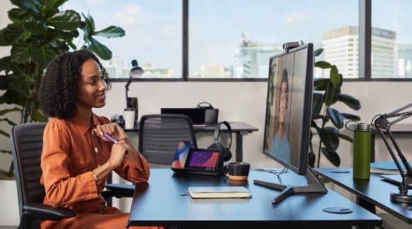 Seated person engaged in a virtual meeting. There is one colleague on the monitor.