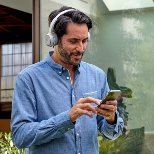 A person in headphones checks a mobile device.
