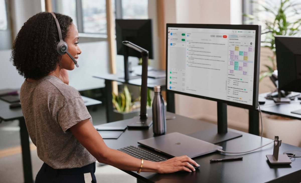 A professional works at a standing desk, and wears a headset.