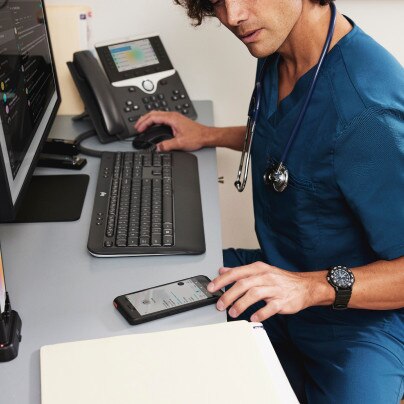 A health professional uses various technologies, including an IP phone.