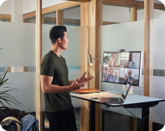 Person at a standing desk participating in a hybrid work virtual meeting.