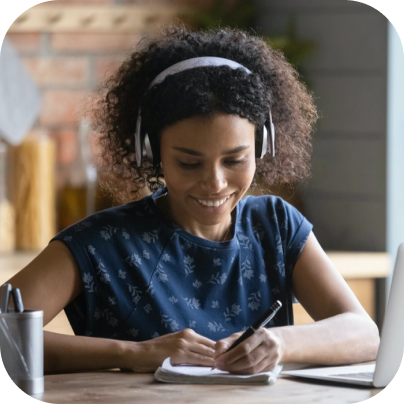 A person with a noise cancelling headset writes in a notebook.