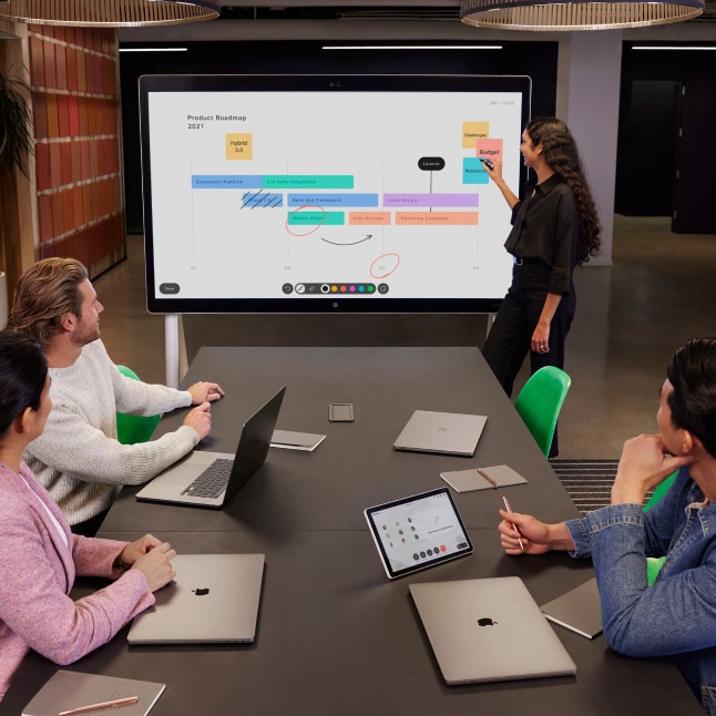 4 people holding a live conference with one presenting at a large digital whiteboard