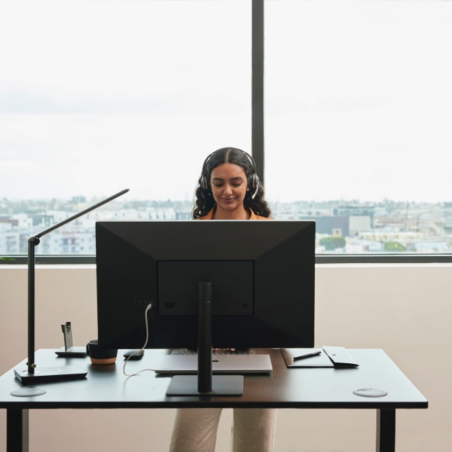 person working at standing desk, possibly on a call/video conference