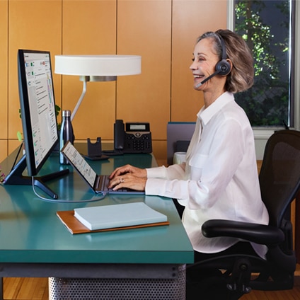 Busy looking worker at desk with mobile phone, desk phone, keyboard, and mouse
