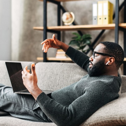 Person nimmt entspannt auf der Couch einen Webex-Anruf entgegen