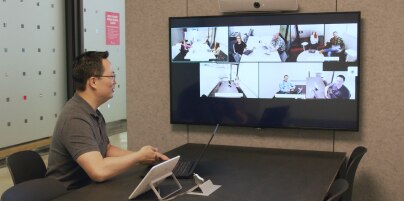 A T-Mobile employee sits in a conference room, engaging in a Webex Meeting with colleagues.