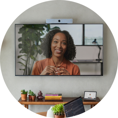 A TV screen with a webcam on top of it shows a person engaged in a video conference.