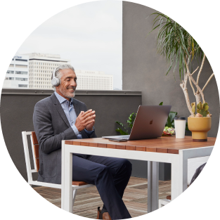 Person outside at a table working/conferencing on laptop