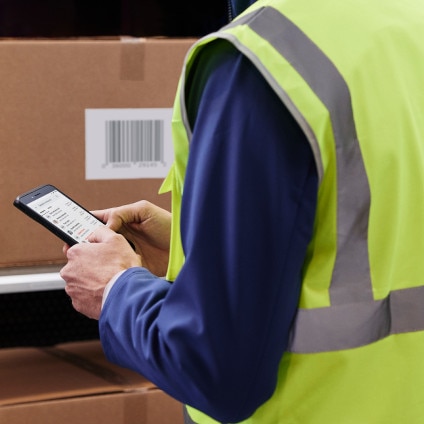 Person in warehouse/stock room using mobile device to work or message