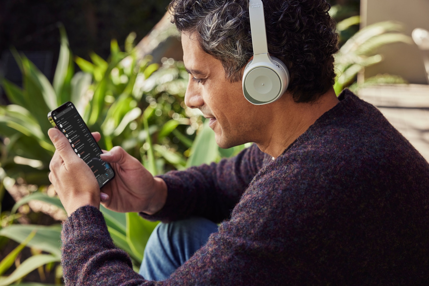 Person outside wearing headphonse using phone to work/collaborate