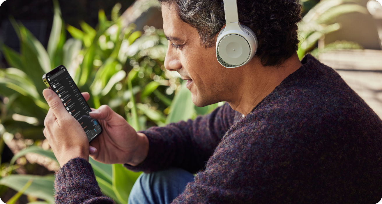 Person outside wearing headphonse using phone to work/collaborate