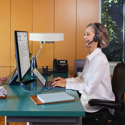 Person at desk working on laptop with desktop monitor