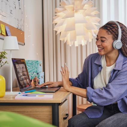 Person in bedroom/dorm room conferencing at desk on laptop