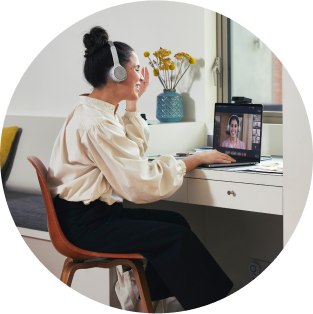 Person meets with a colleague from a laptop via Webex Calling, using collaboration devices such as the Webex headset and the Webex Desk Camera.