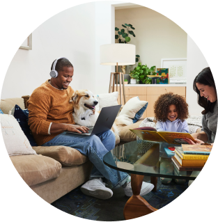 User collaborates while working remotely via Webex Calling from the living room, with family members and a pet nearby.