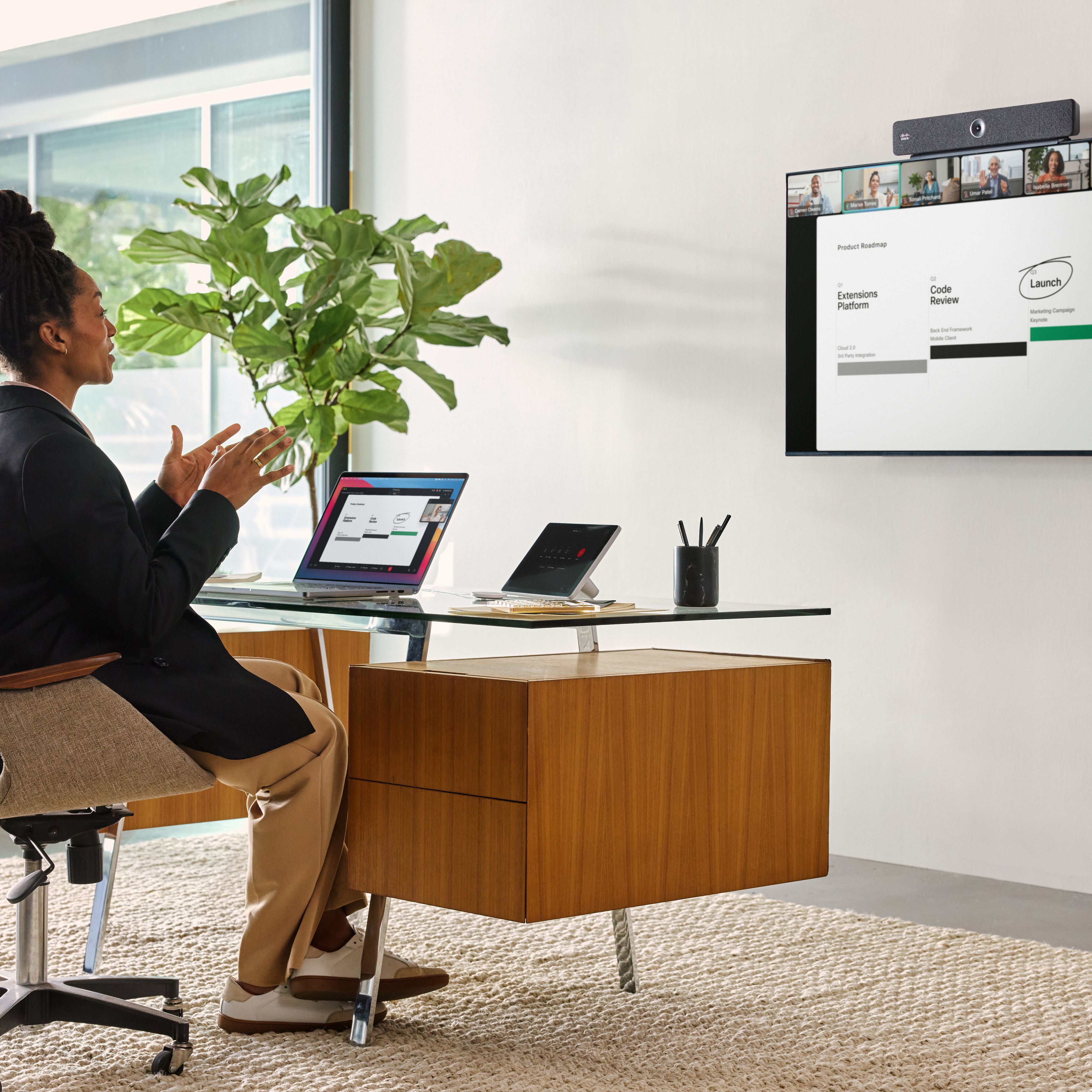 A professional sits at a desk, video conferencing with several colleagues via Webex