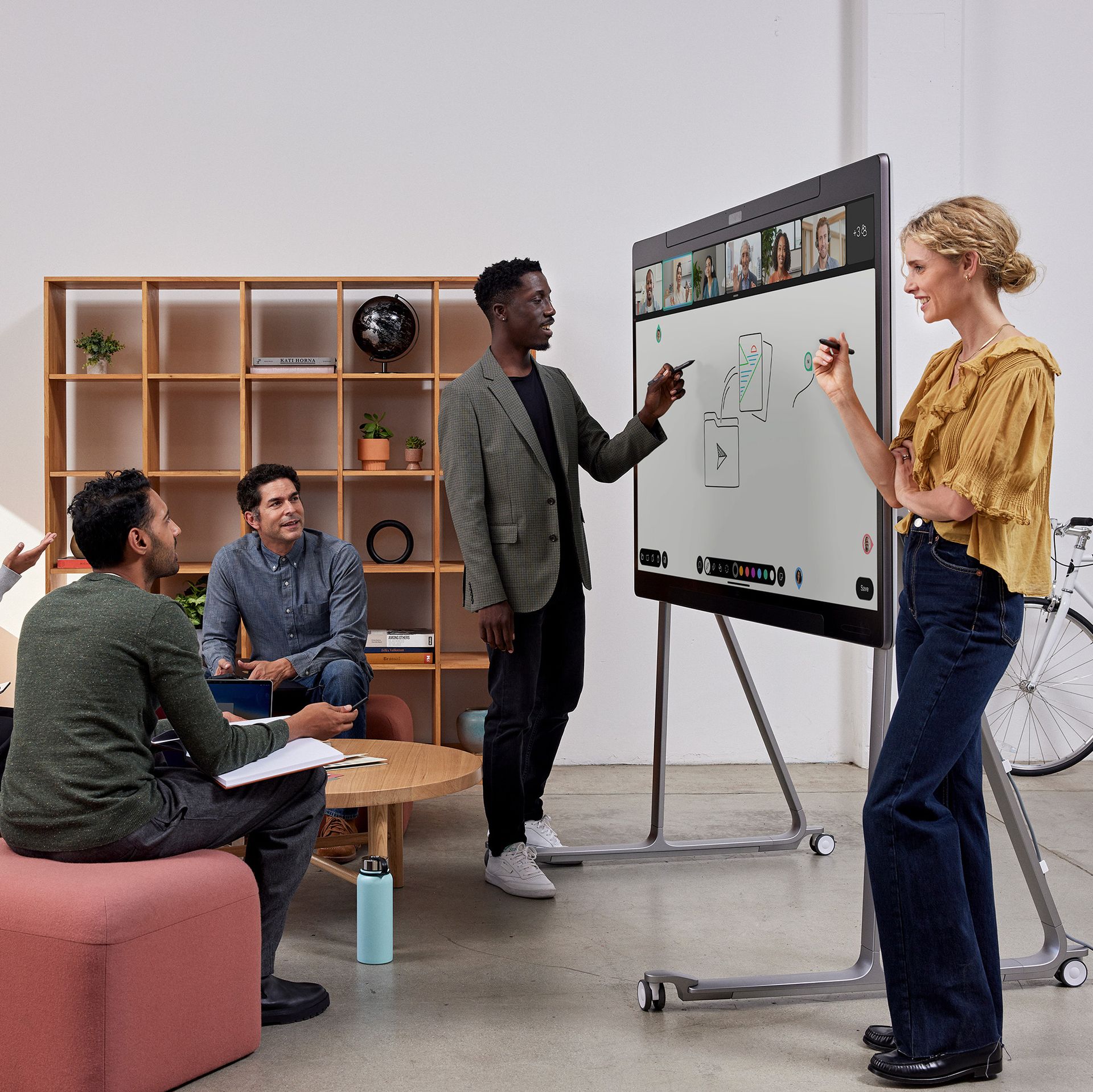 Five colleagues collaborate using a Cisco Board Pro, working with other colleagues who have video conferenced in.