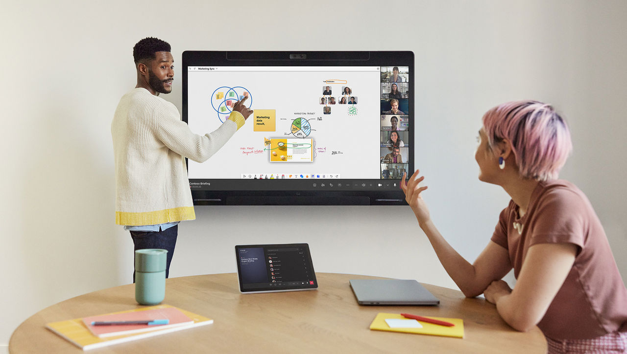 Two colleagues collaborating in a meeting room, using a large interactive display for a brainstorming session.