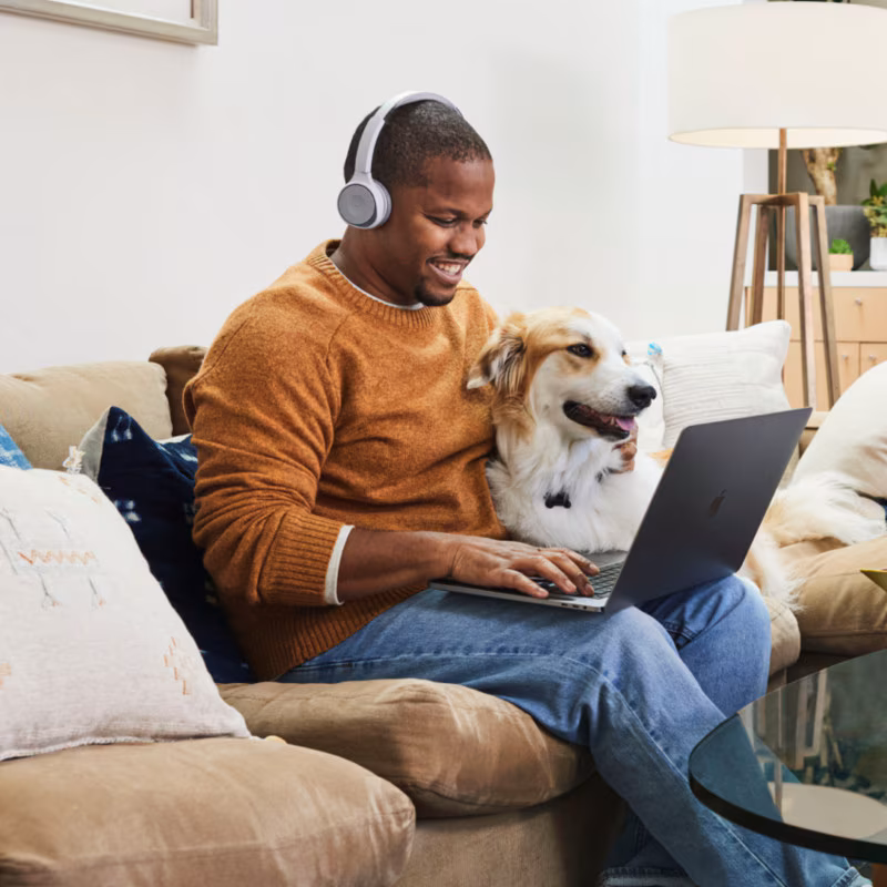 happy looking customer at home using laptop with dog