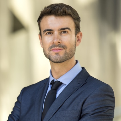 An attorney wearing a suit looks directly at the camera.