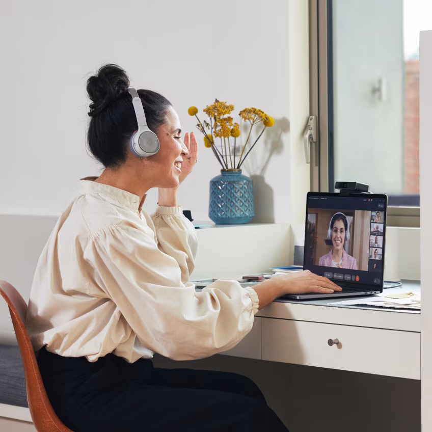 Person video conferences with colleagues from her home office via Webex Meetings on a laptop.