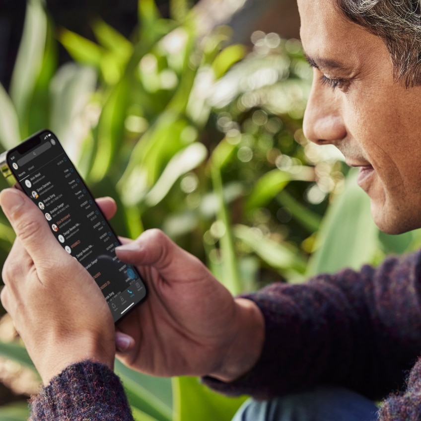 A professional working outdoors checks the Webex App on his iPhone.