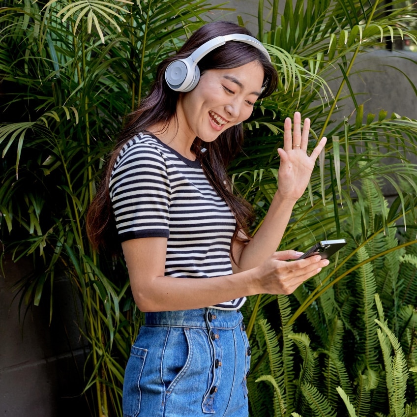 A professional wearing a headset collaborates outside on-the-go via a Webex video meeting on her iPhone.