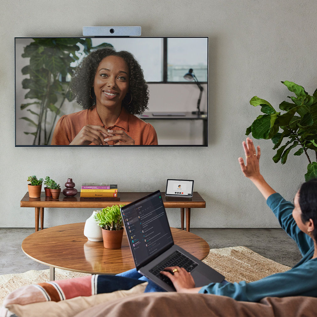 Person video conferences with a colleague via Webex, sharing the meeting to a Webex device from a laptop using Apple AirPlay.