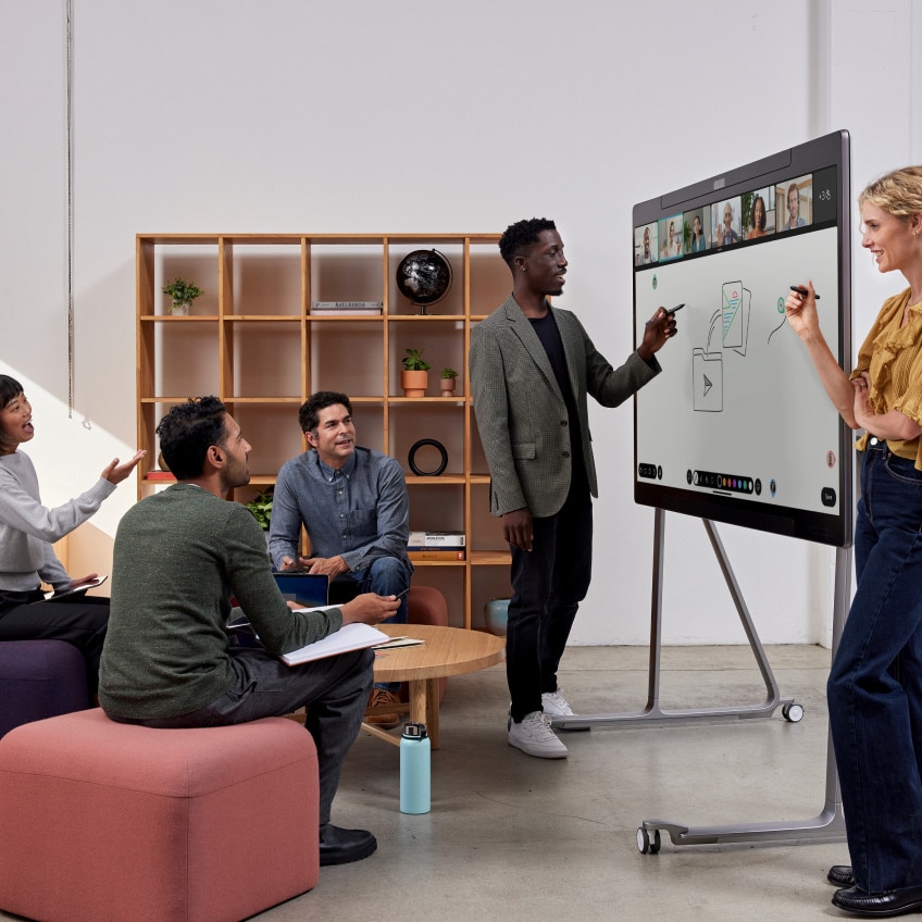 Five colleagues collaborate on a digital whiteboard, working with other colleagues who have video conferenced in.