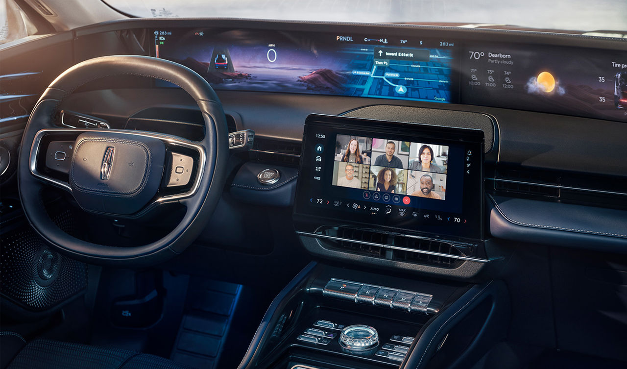 Driver uses Ford dashboard to display grid view Webex video conference with in-office and remote workers.